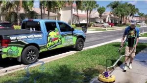 An Oleyn's service technician washing a concrete walkway next to the Oleyn's service vehicle