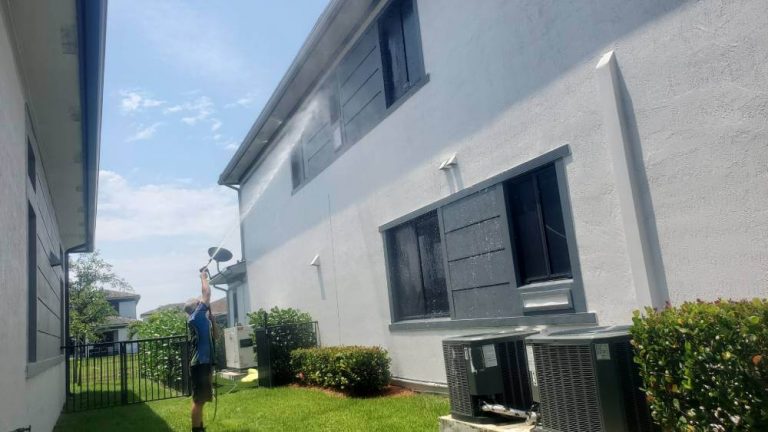 An Oleyn's service member soft washing the side of a house